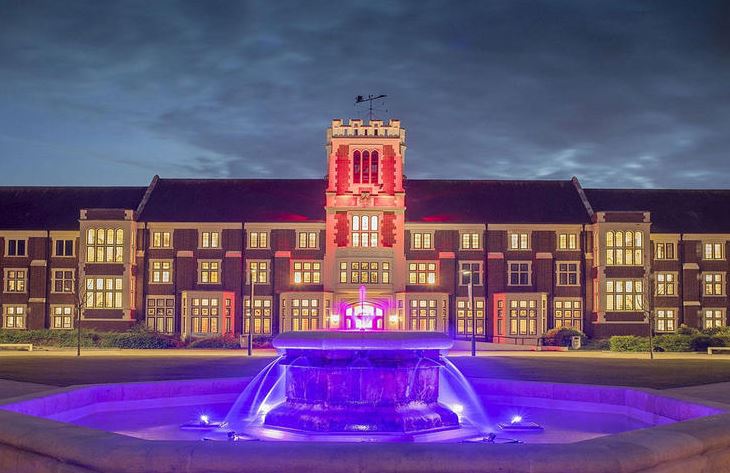 Hazlerigg building at night, the fountain in front is spotlit in purple